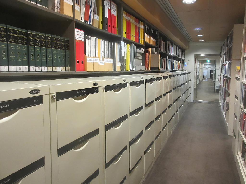 <p>Vertical file cabinets in the Research Library stacks and an artist file for Bronwynne Cornish</p>