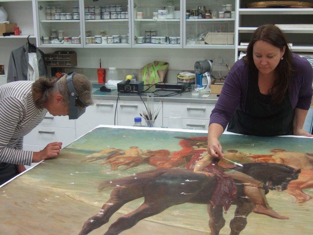 <p>Paintings Conservators Nel Rol and Ingrid Ford cleaning the paint surface</p>