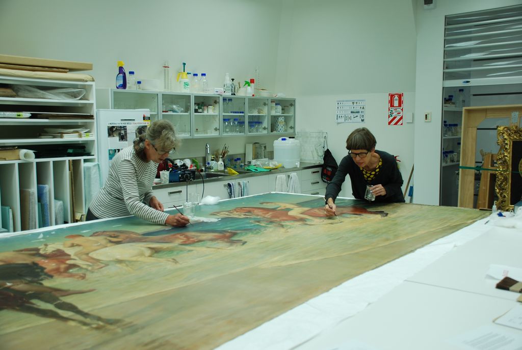 <p>Principal Conservator Sarah Hillary and Paintings Conservator Nel Rol consolidating the damaged areas of paint</p>