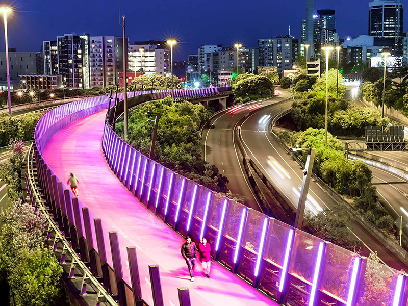 https://cdn.aucklandunlimited.com/corporate/assets/media/about-us-gallery-people-walking-and-jogging-across-te-ara-i-whiti-the-pink-lightpath-at-night-in-auckland.jpg