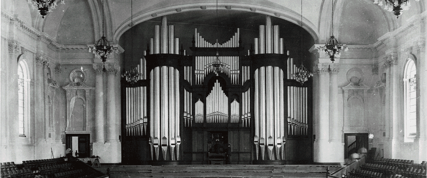 Gif switching between a black and white photo of the first 1911 Norman & Beard organ of the Auckland Town Hall, switching to a recent colour photo of the 2010 Klais organ.