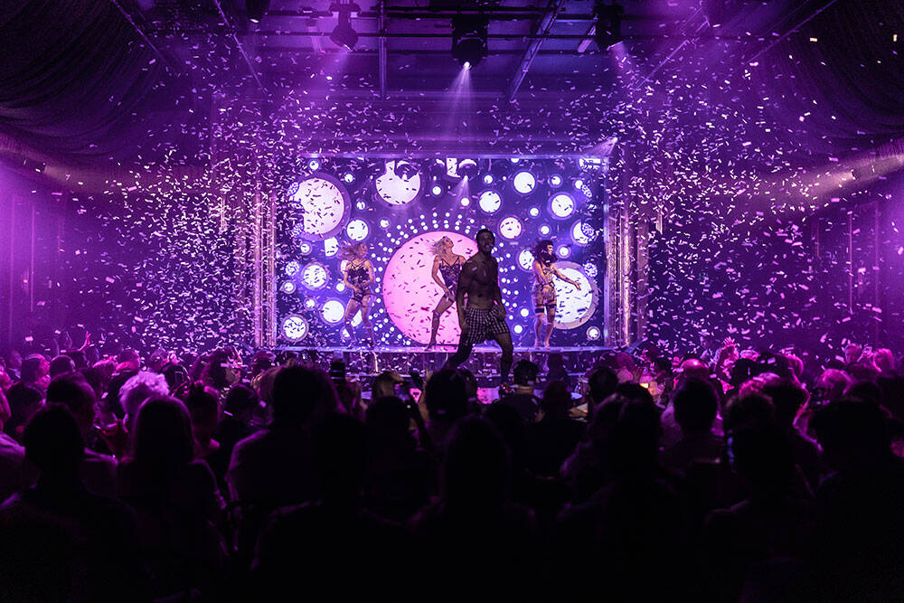 Circus performers on stage with glitter going into the crowd