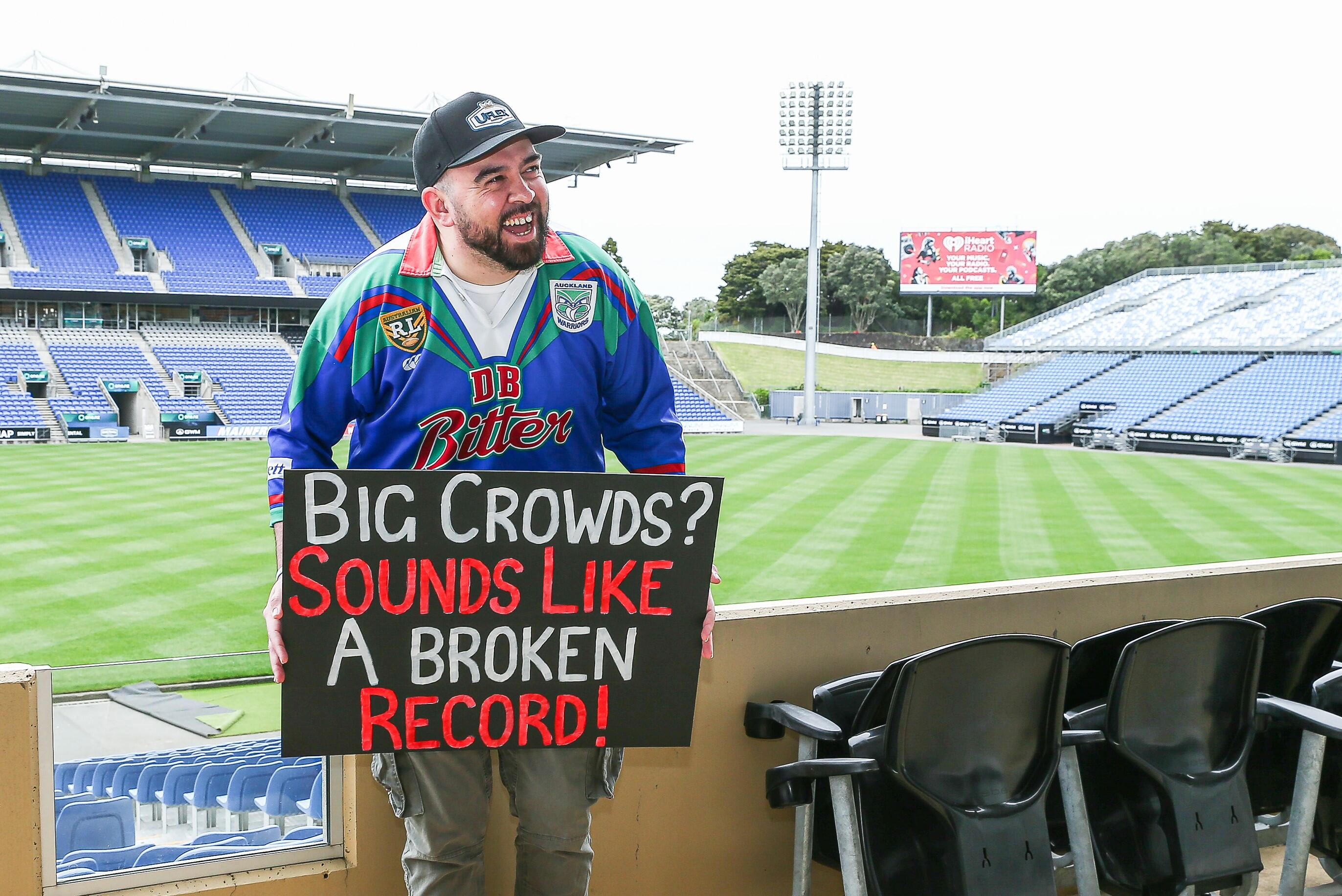 Warriors superfan Robert Harris, better known as The Sign Guy, laughs at Go Media Stadium in his Warriors jersey, holding a sign celebrating the record breaking season